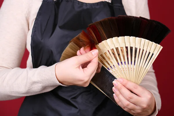 Hair stylist with hair samples of different colors, close-up, on color background