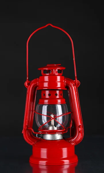Red kerosene lamp on black background