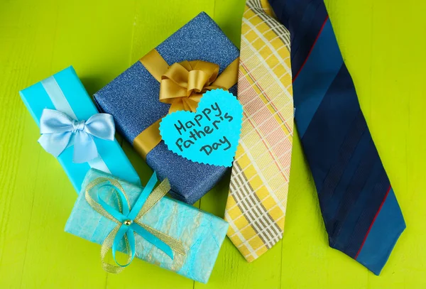 Happy Fathers Day tag with gift boxes and tie, on wooden background