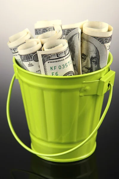 Money in trash can, on dark background