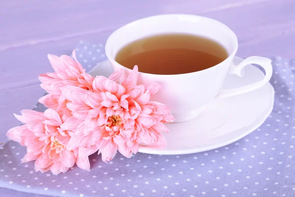 Pink chrysanthemums and cup of tea on wooden table