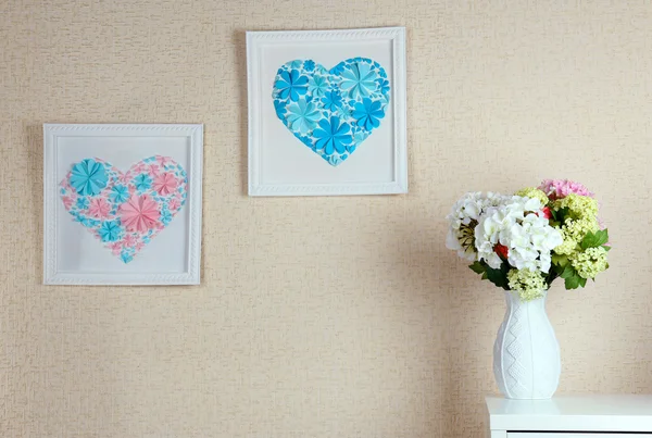 Beautiful handmade pictures with heart from paper flowers on wall