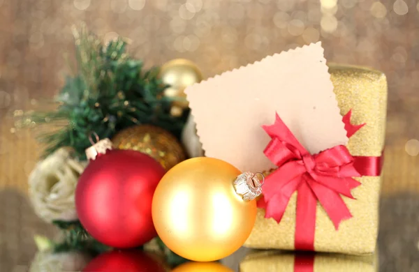 Gift boxes with blank label and Christmas decorations on table on bright background