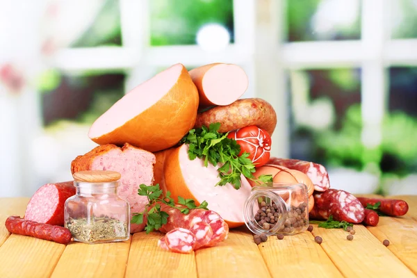 Lot of different sausages on wooden table on window background