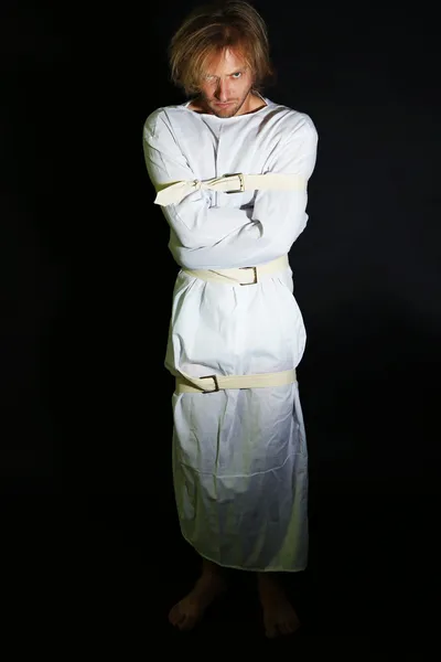 Mentally ill man in strait-jacket on black background