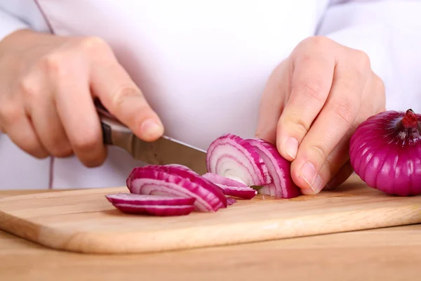 Female hands cutting bulb onion, close up