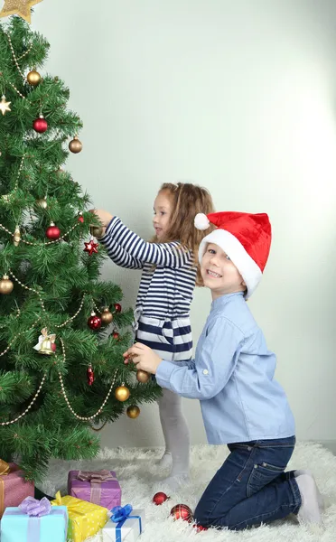 Kids decorating Christmas tree with baubles in room