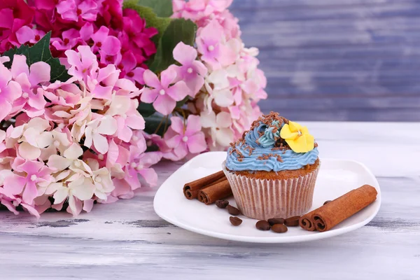 Tasty cupcake with butter cream, on plate, on color wooden background