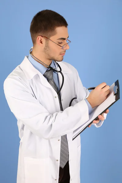 Male Doctor standing with folder, on blue background