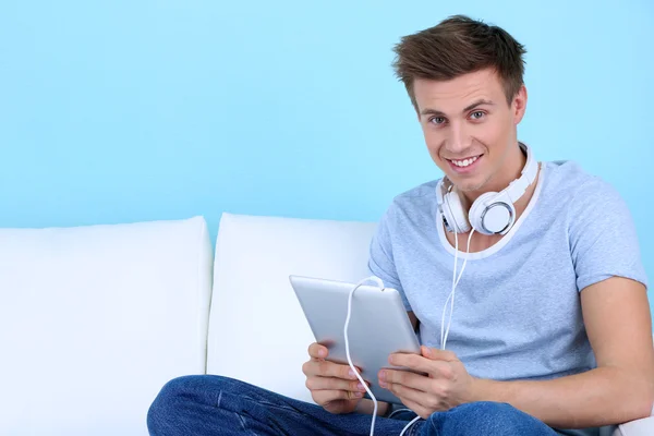 Guy sitting on sofa and listening to music on blue background