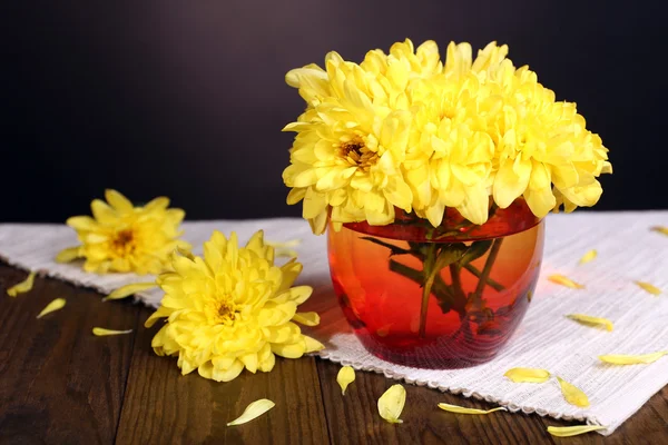 Beautiful chrysanthemum flowers in vase on table on dark background