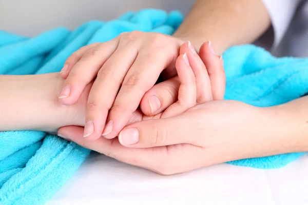 Medical doctor holding hand of patient, on light background