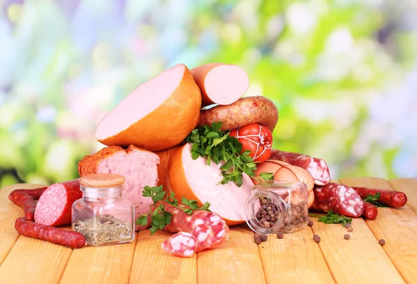 Lot of different sausages on wooden table on natural background