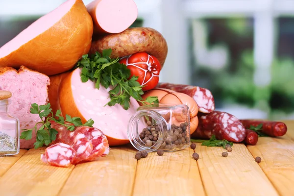 Lot of different sausages on wooden table on window background