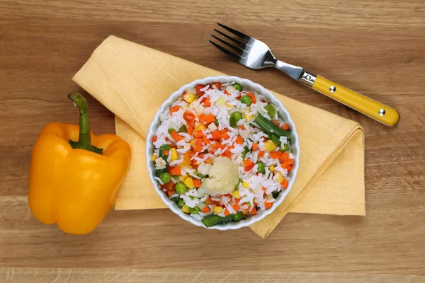 Cooked rice with vegetables on wooden table