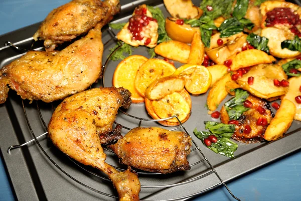 Homemade fried chicken drumsticks with vegetables on pan, on wooden background