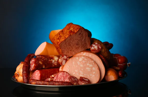 Lot of different sausages on salver on dark colorful background