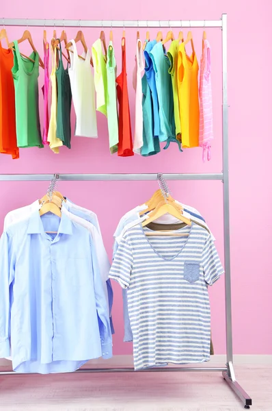 Different clothes on hangers, on pink background