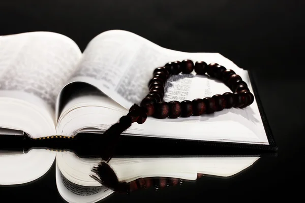 Russian bible and wooden rosary on black background