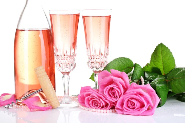 Composition with pink sparkle wine in glasses, bottle and pink roses isolated on white