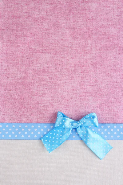 Color ribbon and bow on two color fabrics background