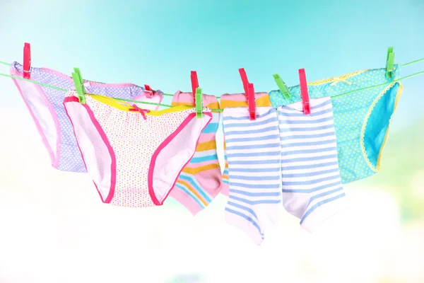 Baby clothes hanging on clothesline, on bright background