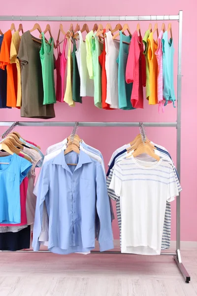 Different clothes on hangers, on pink background