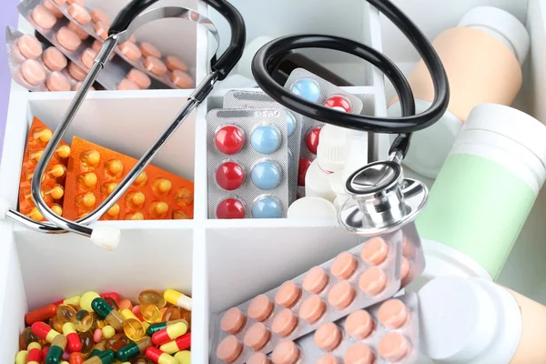 Medical pills, ampules in wooden box, on color background