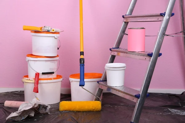 Buckets with paint and ladder on wall background. Conceptual photo of repairing works in room