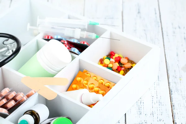 Medical pills,stethoscope, ampules in wooden box, on color background