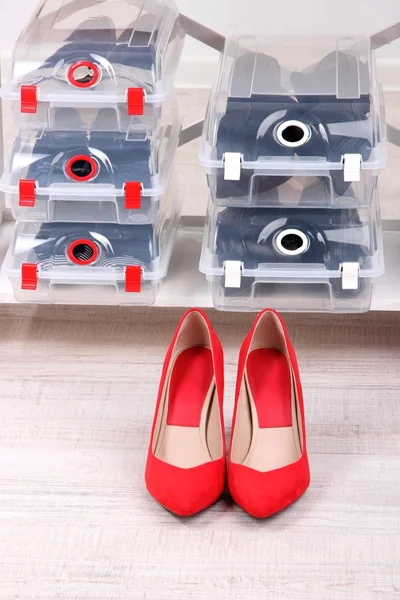 Shoes in plastic boxes and female shoes on floor in room