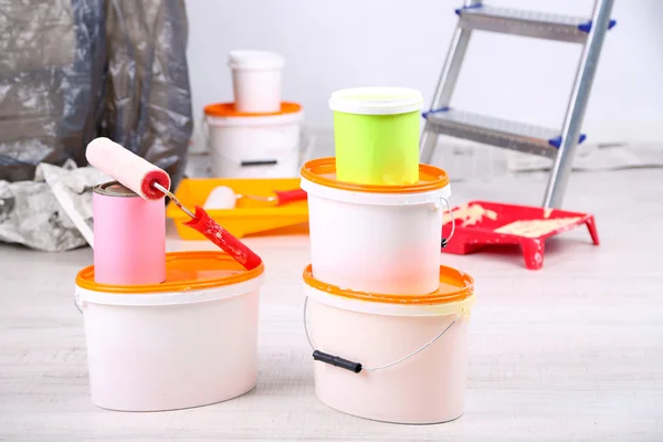 Buckets with paint, wrapped sofa and ladder on wall background. Conceptual photo of repairing works in room