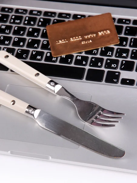Credit card with fork and knife on computer keyboard close up
