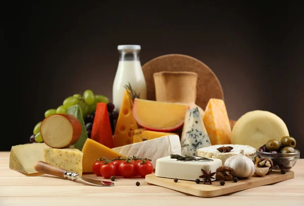 Tasty dairy products on wooden table, on dark background