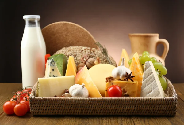 Basket with tasty dairy products on wooden tray, on dark background