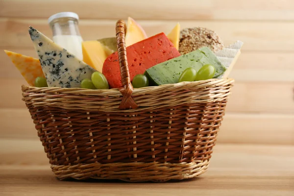 Basket with tasty dairy products on wooden background