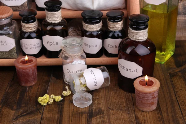 Composition with empty page, candle and historic old pharmacy bottles with label on wooden background