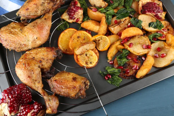 Homemade fried chicken drumsticks with vegetables on pan, on wooden background