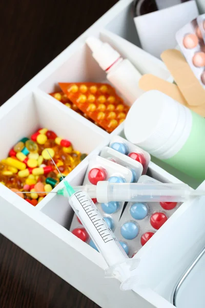 Medical pills, ampules in wooden box, on color background