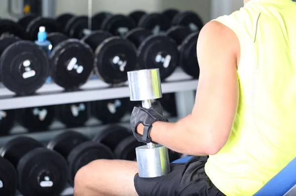 Guy with dumbbells on gym background close-up