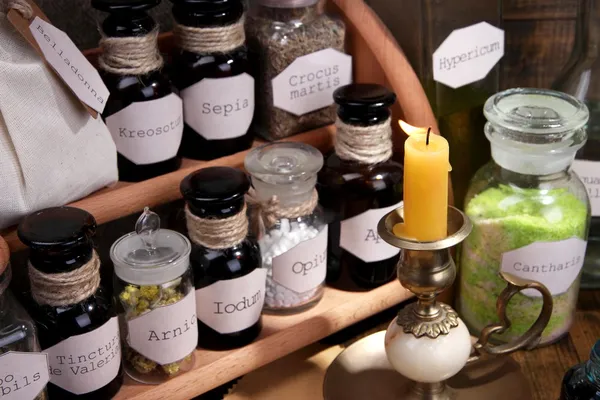 Composition with empty page, candle, mortar and historic old pharmacy bottles with label on wooden background