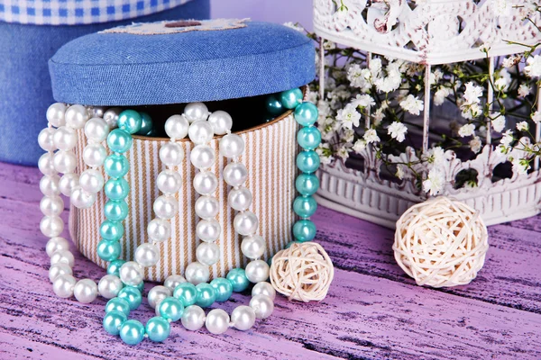 Decorative boxes with beads and flowers on table close up
