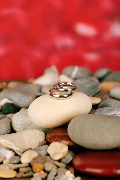 Wedding rings on rocks on red background