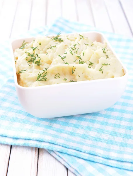 Delicious mashed potatoes with greens in bowl on table close-up