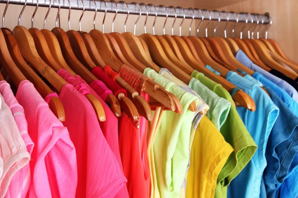 Colorful clothes hanging in wardrobe