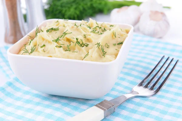 Delicious mashed potatoes with greens in bowl on table close-up