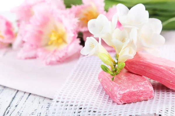 Composition with beautiful  flowers and soap on wooden background