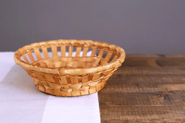 Empty wicker basket on wooden table, on dark background
