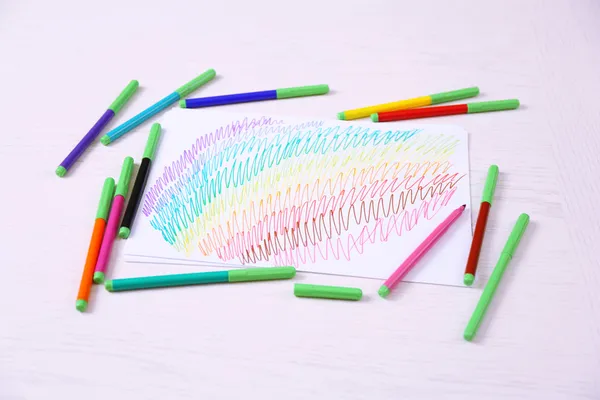 Kids drawing and colored pencils on wooden table