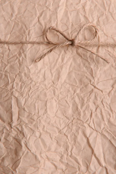 String tied in  bow on beige paper packaging close-up